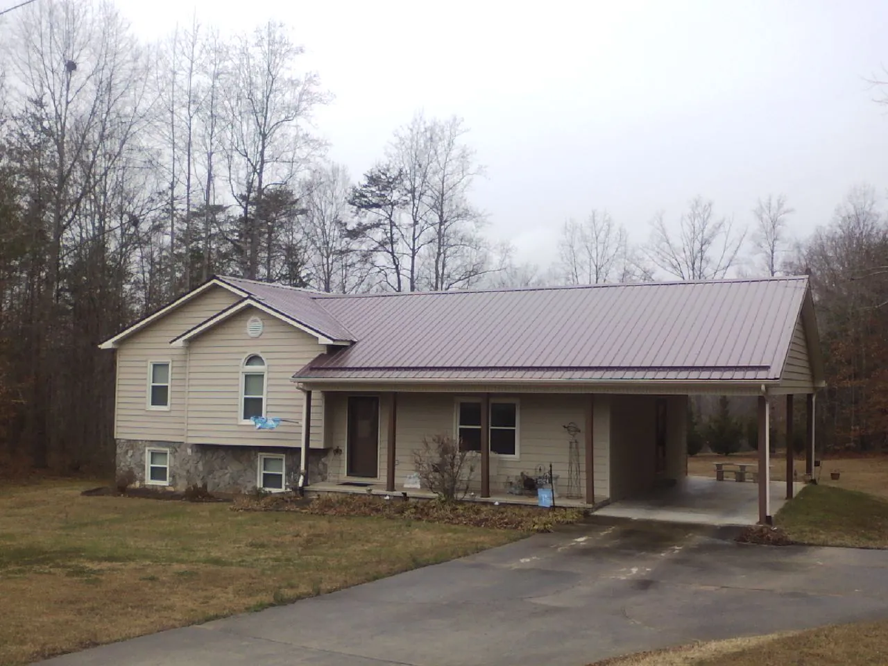 Burgundy metal roof on a tan split level home with an attached carport in Coatesville