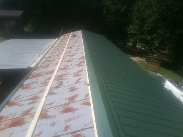Old rusted panels beside newly installed green metal roofing — Wind Damage Roof Repair by Roofing Brothers in Coatesville