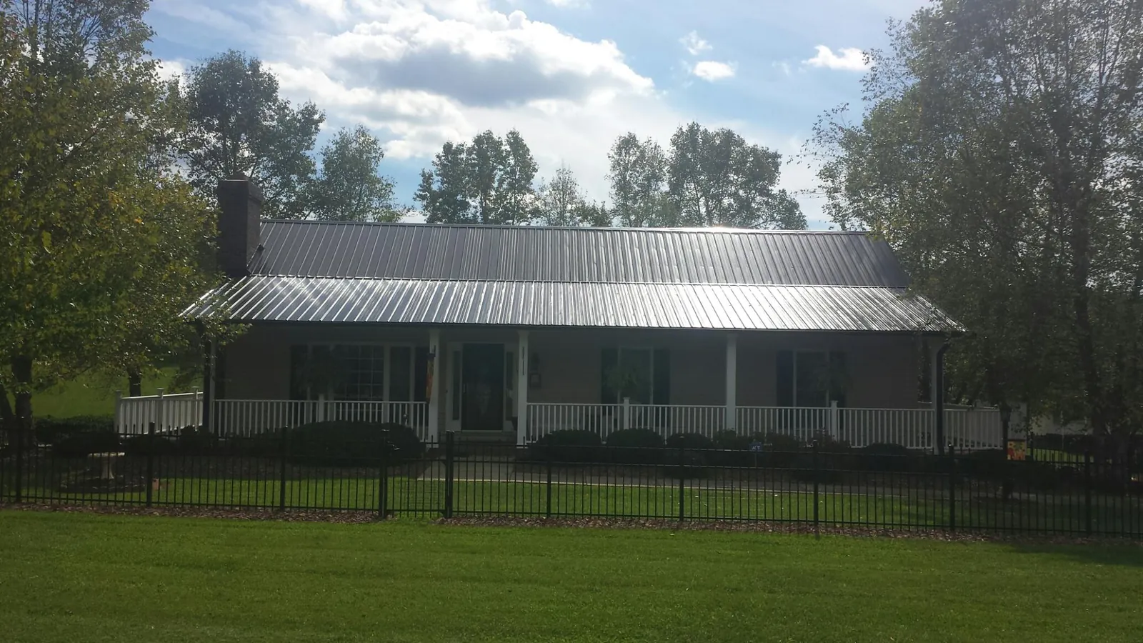 Gray metal roof on a brick ranch with a full width front porch — Gutter Guard Installation work by our crew in Coatesville