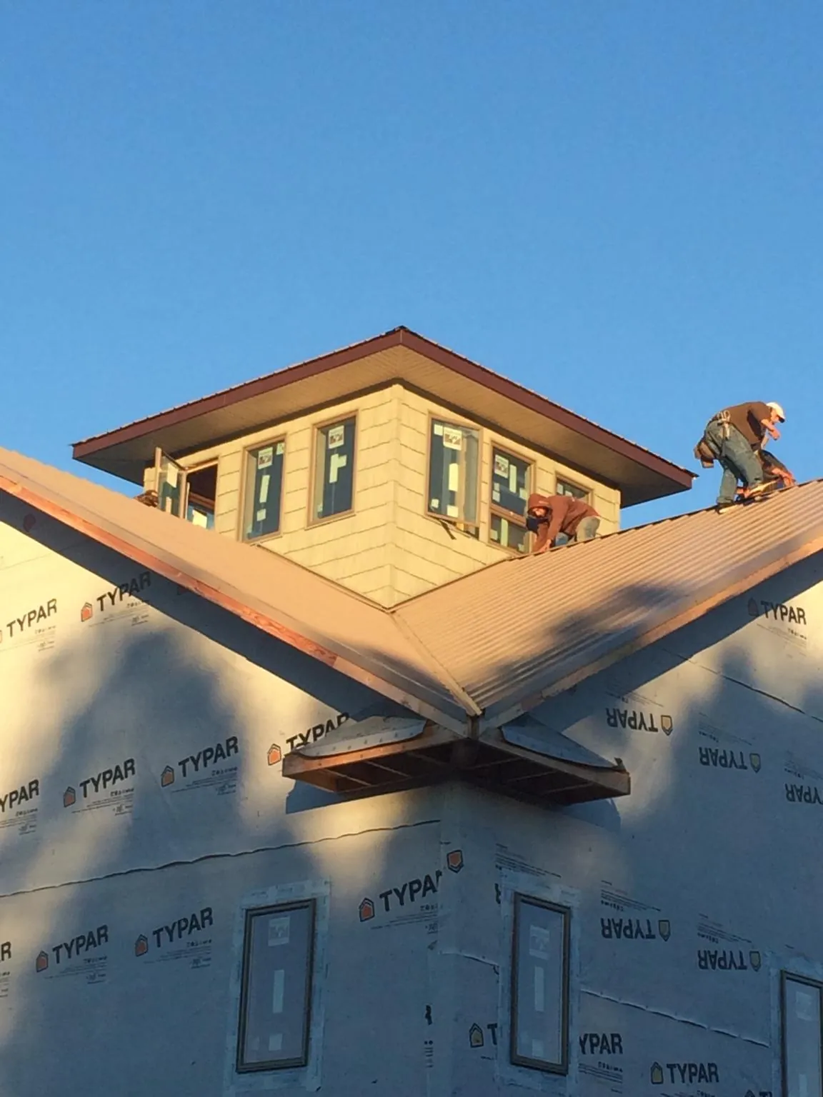 Roofers working around a rooftop cupola on a new metal roof at sunset — Roof Waterproofing in Coatesville by Roofing Brothers